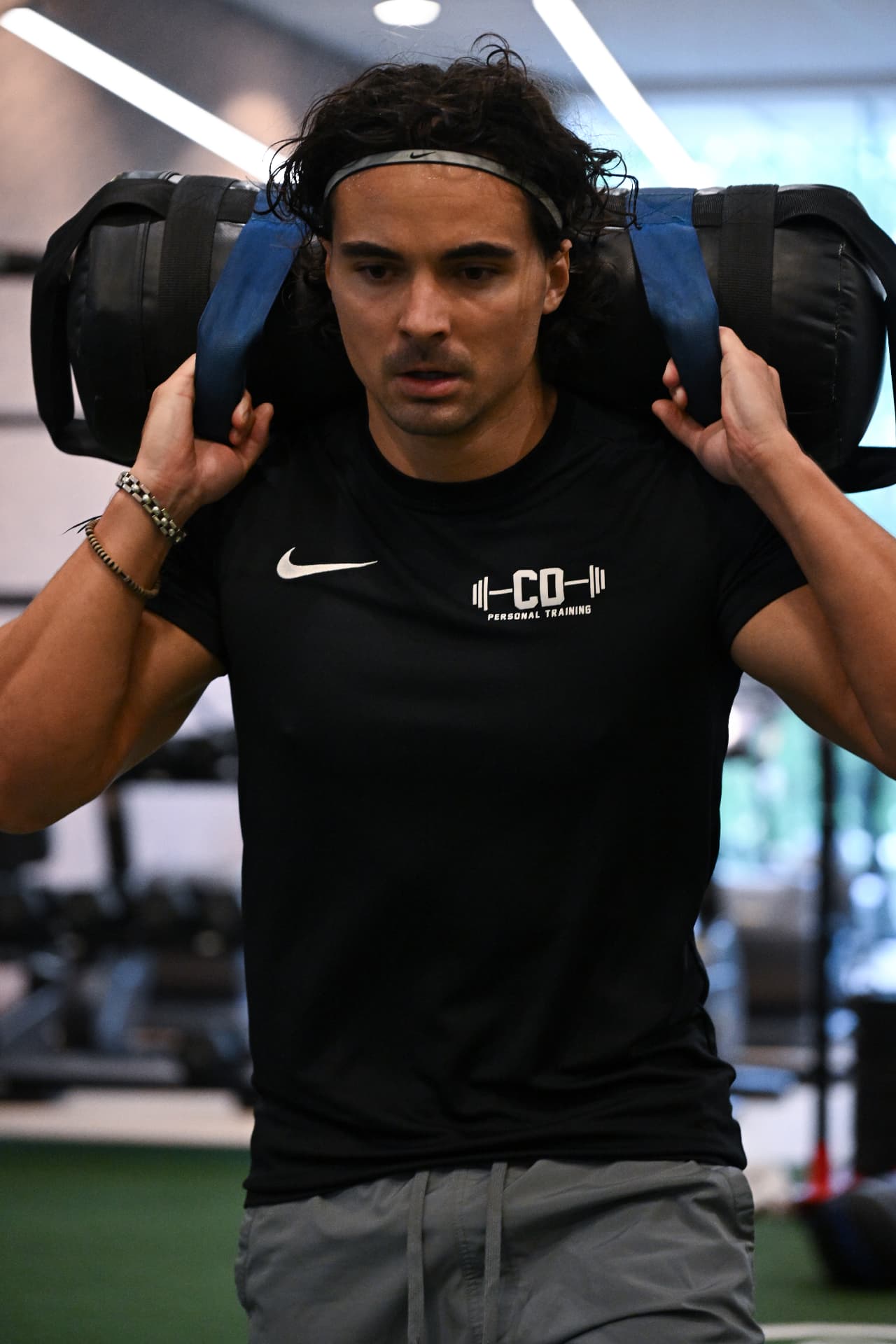 Klant van CD Personal Training traint met een sandbag op zijn schouders